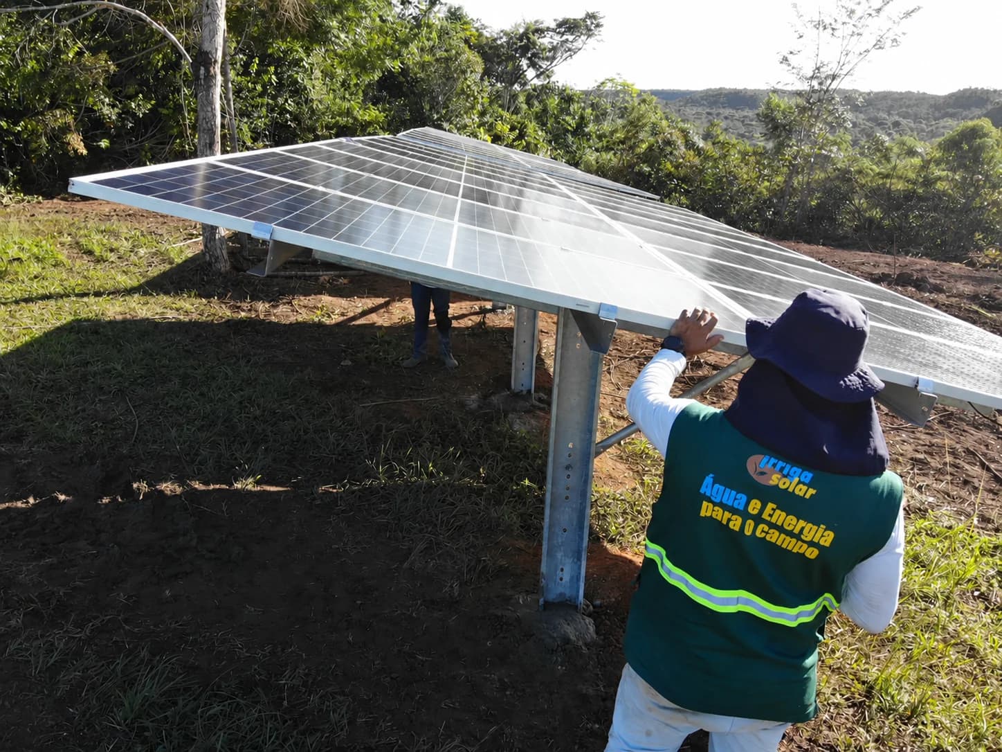 Profissional com colete da Irrigasolar junto aos módulos solares em campo